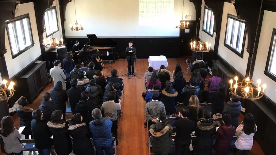 위에서 내려다본 주일예배. 교인들이 자리에서 일어나 있고, 앞쪽에 목사가 서 있다. 왼쪽에 그랜드피아노가 있고 천장에 촛대형 샹들리에가 걸려 있다.
